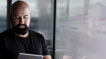 Man looking at tablet with data reflected
