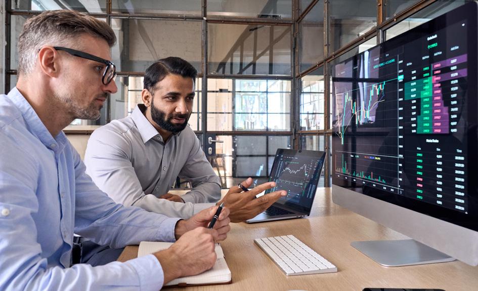 Two men at a desk looking at data on a computer screen